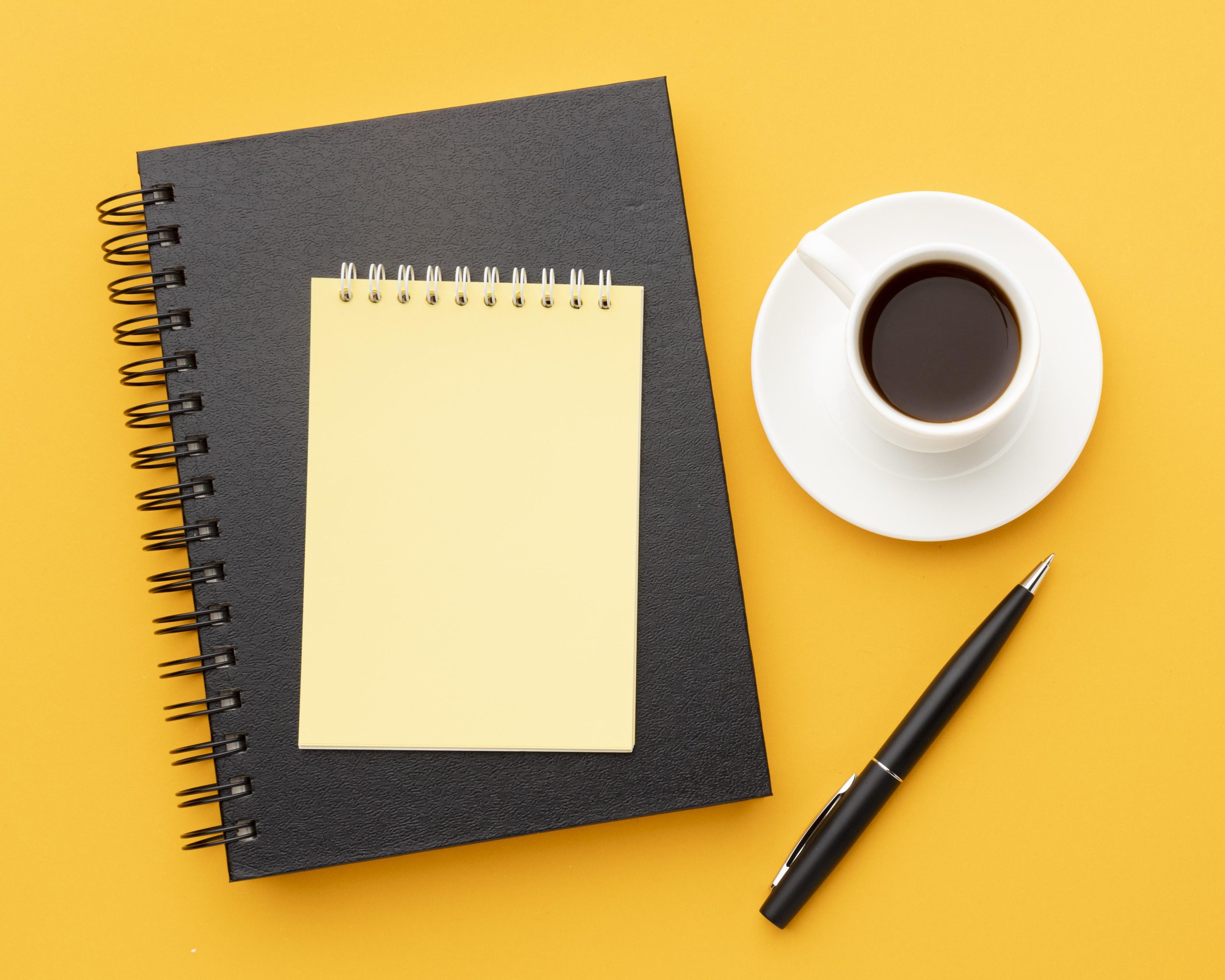 top-view-office-desk-composition-with-empty-notepad